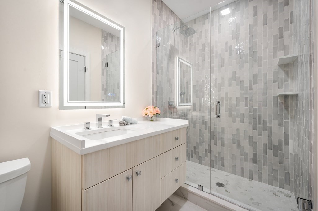 5245 Washington Street, Unit 6 Boston, MA 02132 - Photo 20 of 22 a bathroom with a shower sink vanity and mirror