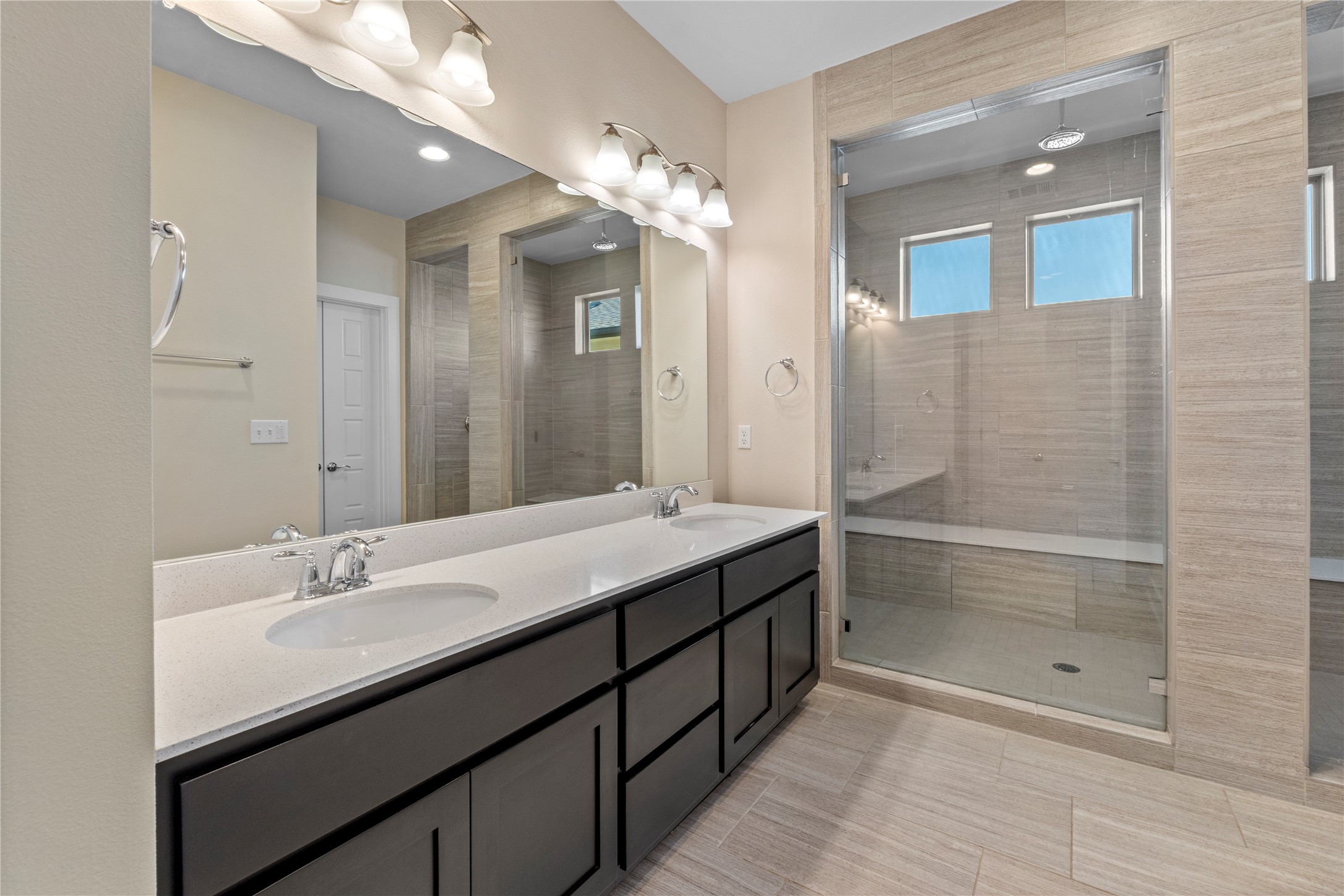 1709 Lawrence Street, Unit 5 Austin, TX 78741 - Photo 25 of 40 Tiled flooring pairs with a modern double vanity and an expansive glass-enclosed walk-in shower.