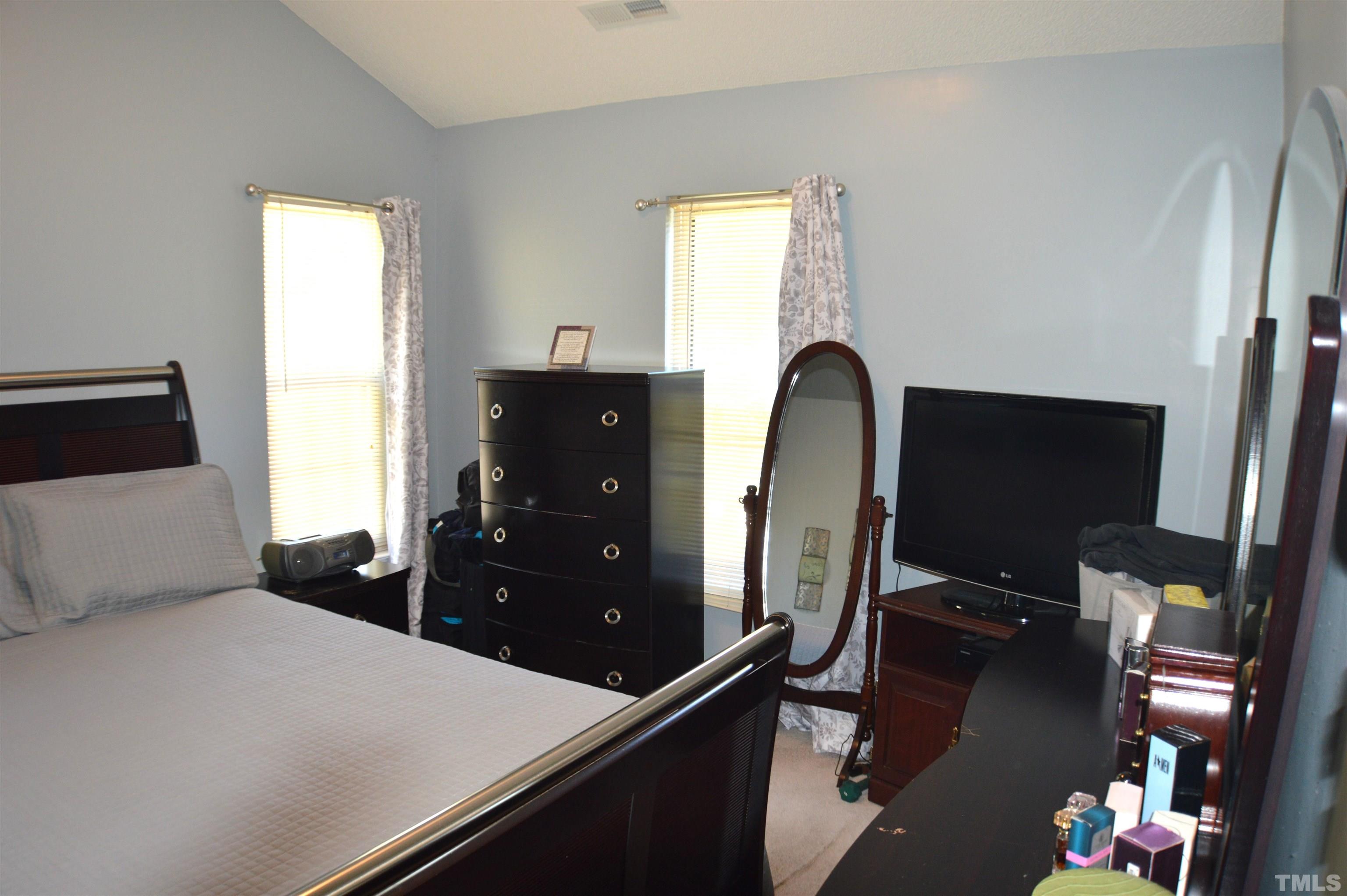 6523 Caverstone Lane Durham, NC 27713 - Photo 19 of 29 a bedroom with a bed and a flat tv screen on dresser
