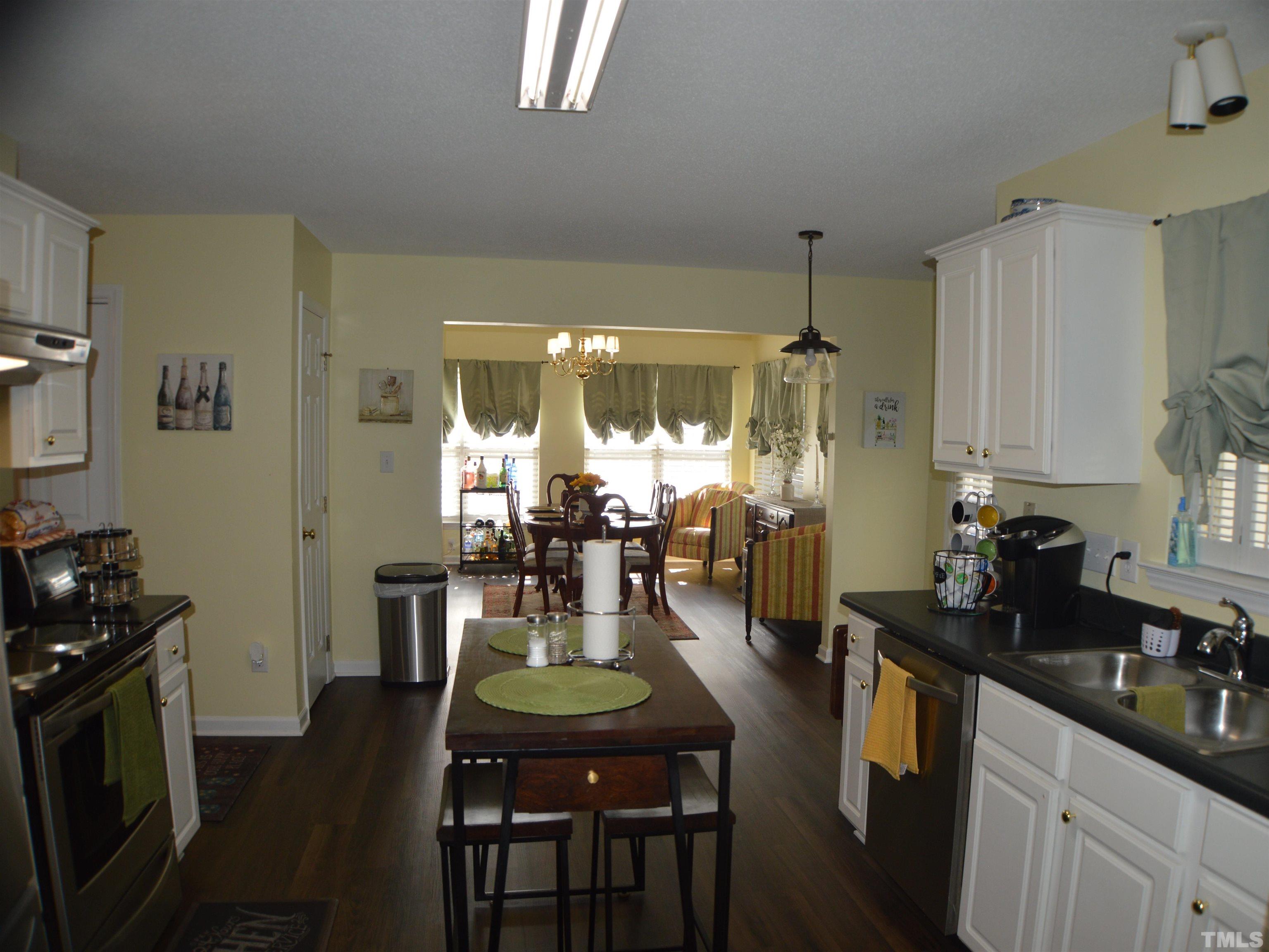 6523 Caverstone Lane Durham, NC 27713 - Photo 6 of 29 a kitchen with sink refrigerator dining table and chairs