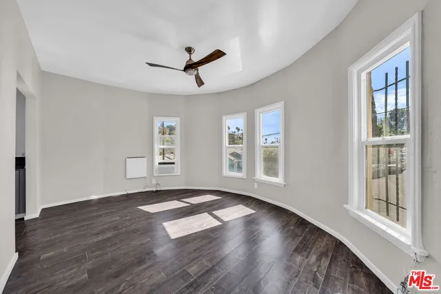 a view of an empty room with wooden floor and a window