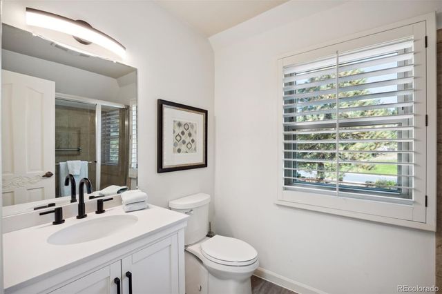 a bathroom with a sink a mirror a toilet and a window