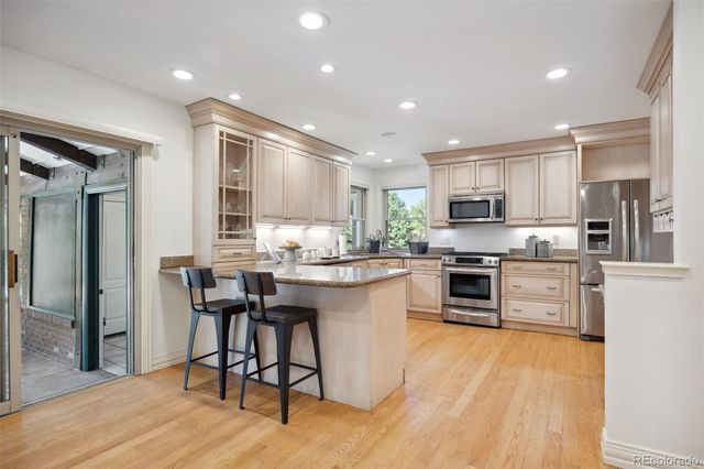 a kitchen with stainless steel appliances kitchen island granite countertop wooden floors and white cabinets