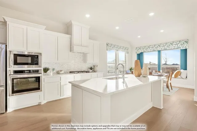 a large white kitchen with a stove a sink a microwave and a dining table