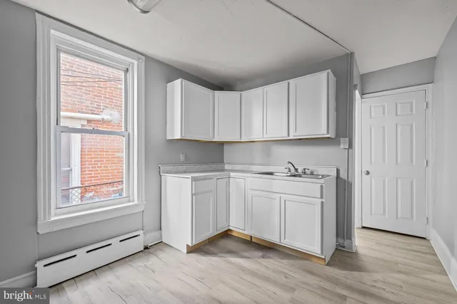 a kitchen with stainless steel appliances granite countertop a stove a sink and white cabinets with wooden floor