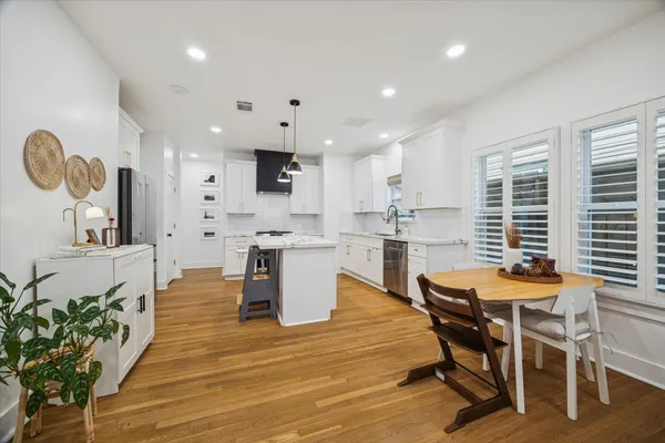 a dining room with stainless steel appliances kitchen island granite countertop a table chairs and a refrigerator