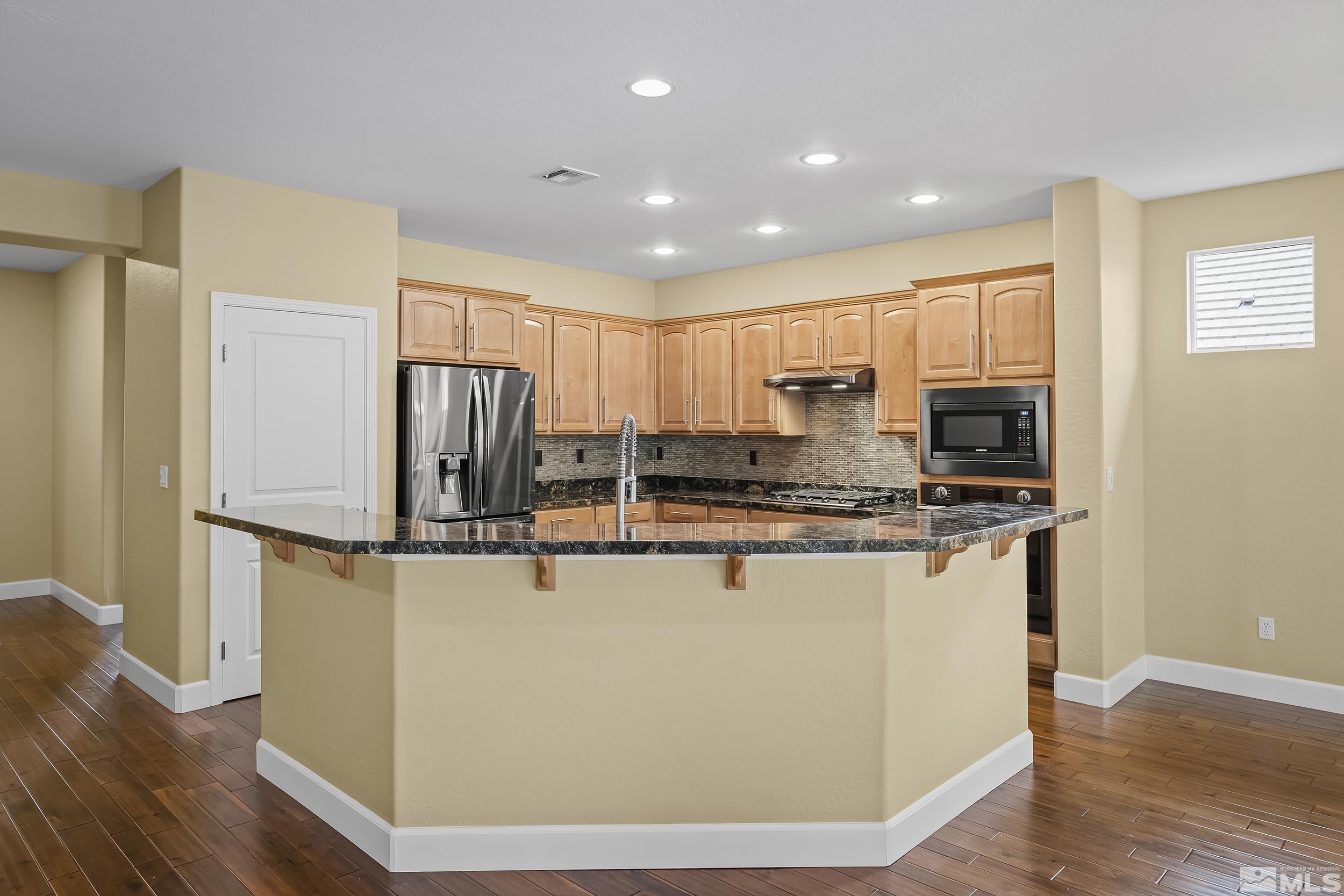 1745 Trail Creek Way Reno, NV 89523 - Photo 10 of 28 a kitchen with stainless steel appliances granite countertop a refrigerator a stove and a microwave with wooden floor
