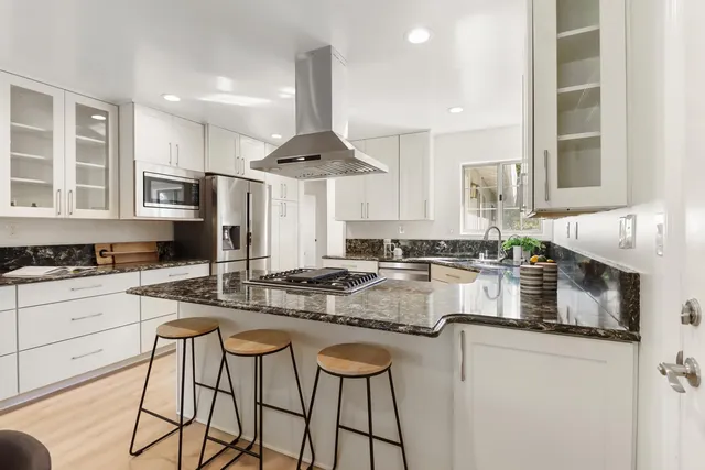 a kitchen with stainless steel appliances a stove a sink and white cabinets