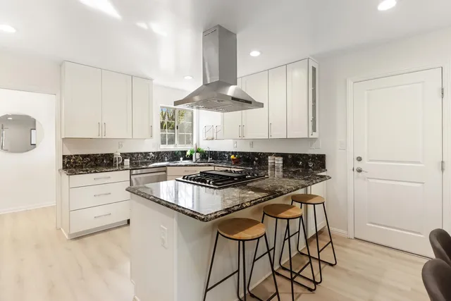 a kitchen with stainless steel appliances a stove a sink cabinets and a window