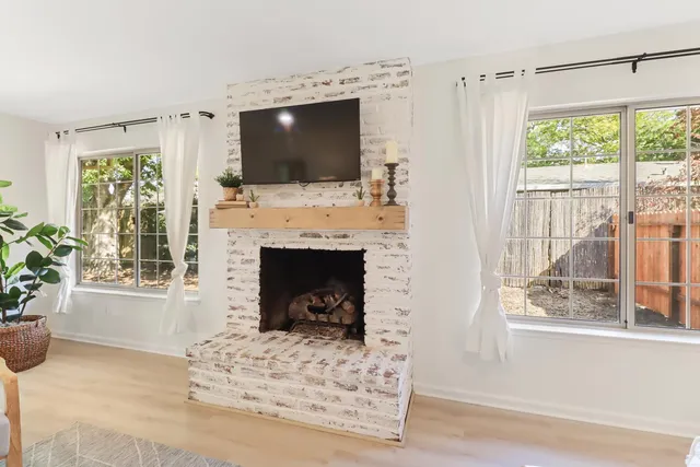 a living room with a fireplace a flat screen tv and a window