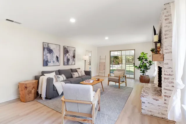 a living room with furniture large window and wooden floor