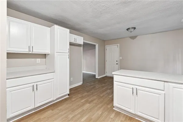 a view of a kitchen with white cabinets and wooden floor
