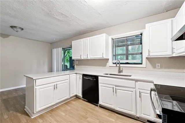 a kitchen with white cabinets sink and window
