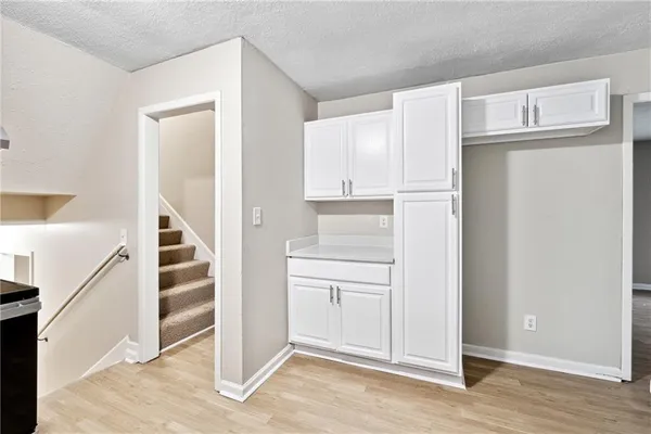a view of a kitchen with white cabinets and refrigerator