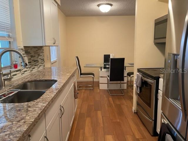 2305 Northeast 38th Street Ocala, FL 34479 - Photo 12 of 34 a kitchen with a sink a stove top oven a refrigerator and a stove with wooden floor