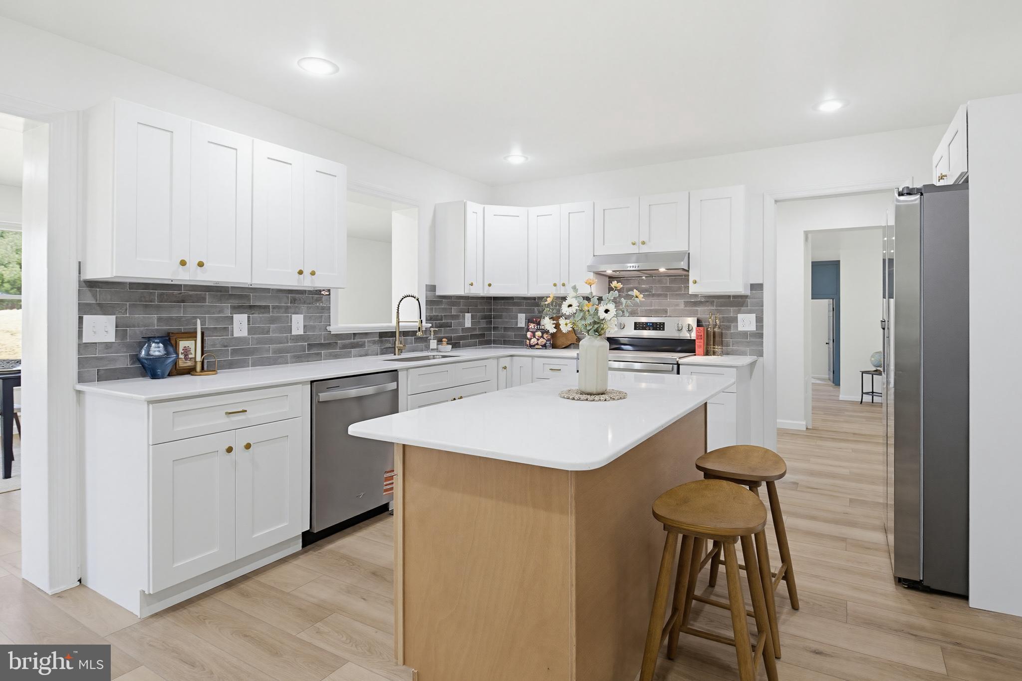 112 Sawmill Road Elizabethtown, PA 17022 - Photo 4 of 56 a kitchen with stainless steel appliances kitchen island a sink a refrigerator and white cabinets with wooden floor