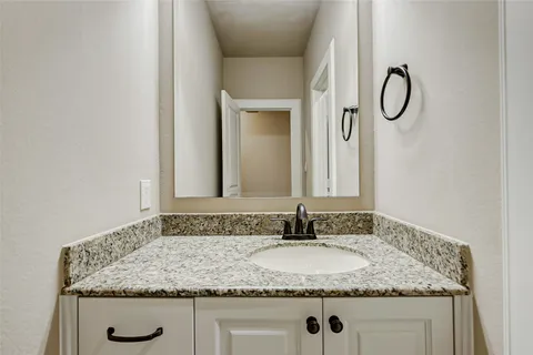 a bathroom with a granite countertop sink and a mirror
