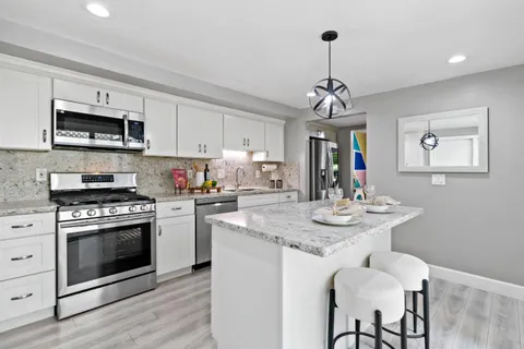 a kitchen with stainless steel appliances granite countertop a sink stove and microwave