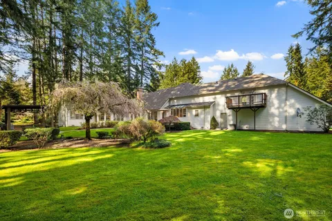 a view of a house with a big yard and large trees