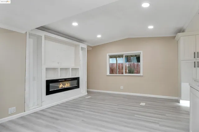 a view of an empty room with wooden floor fireplace and a window
