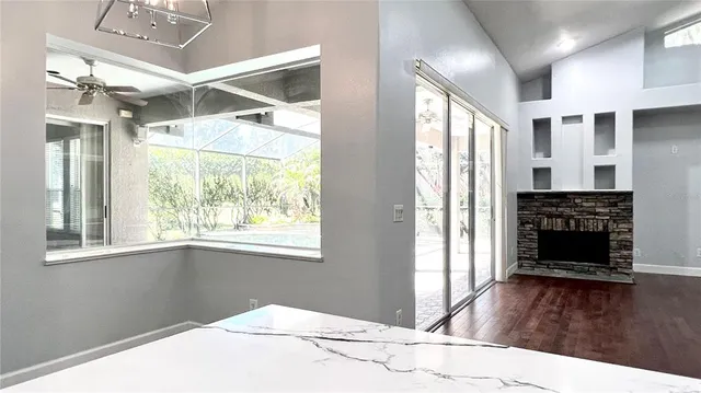 an empty room with wooden floor fireplace and windows