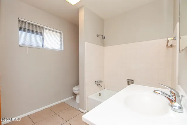 a view of an empty room with window and chandelier fan