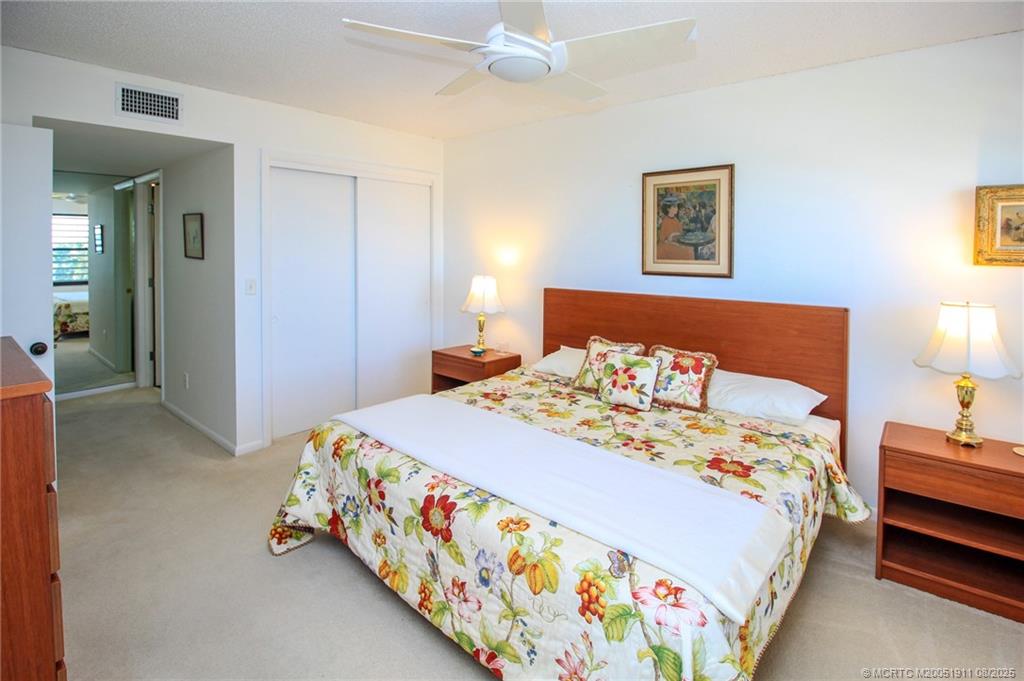 4540 Northeast Sandpebble Trace, Unit 406 Stuart, FL 34996 - Photo 15 of 36 a bedroom with a bed and a lamp on dresser