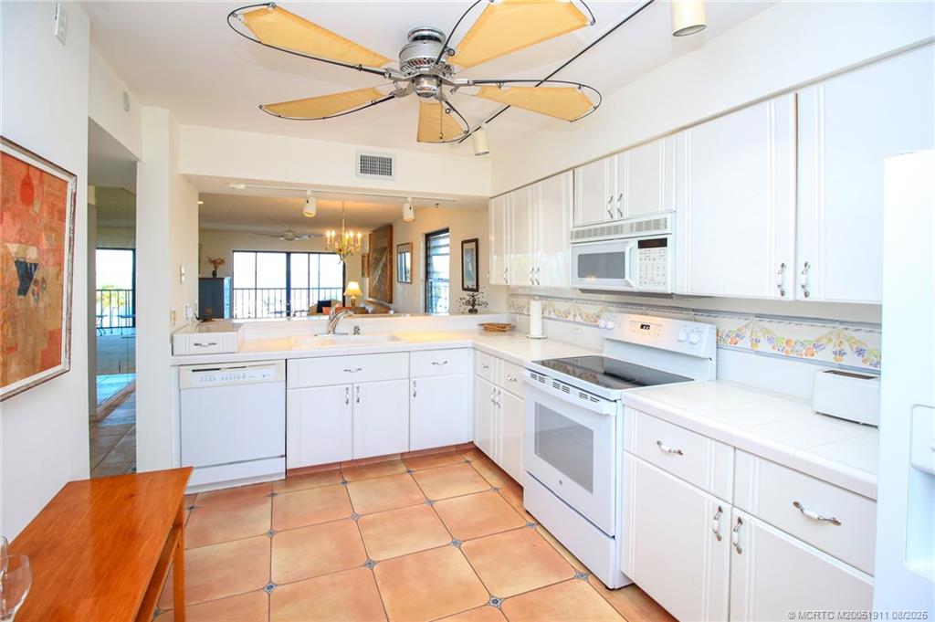 4540 Northeast Sandpebble Trace, Unit 406 Stuart, FL 34996 - Photo 6 of 36 a large white kitchen with cabinets a sink a stove a refrigerator and white cabinets
