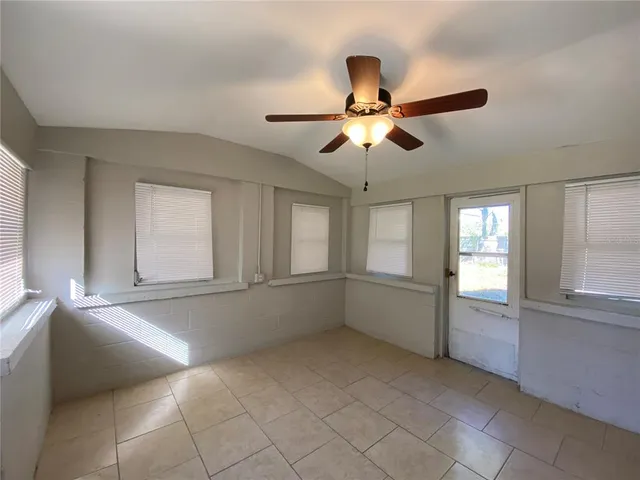 a view of an empty room with window and chandelier fan