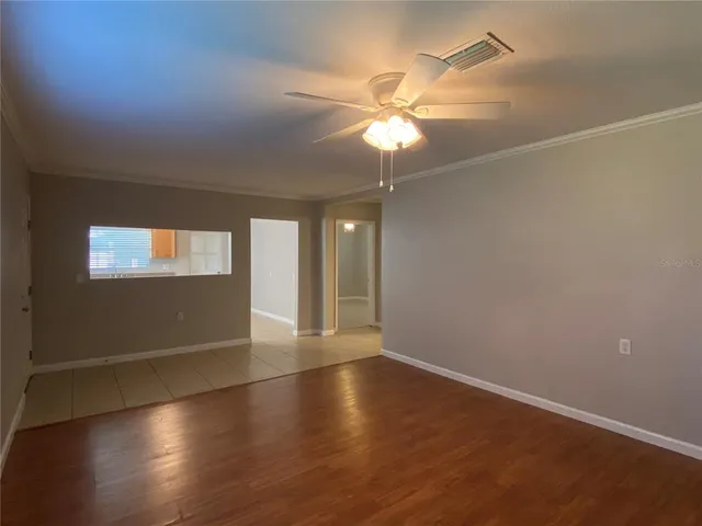 an empty room with wooden floor fan and windows