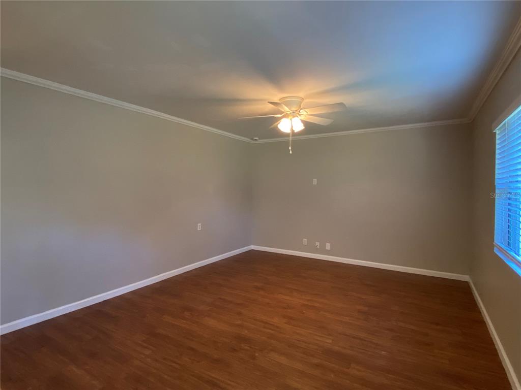 16131 Wallace Street Umatilla, FL 32784 - Photo 4 of 15 an empty room with wooden floor and chandelier fan
