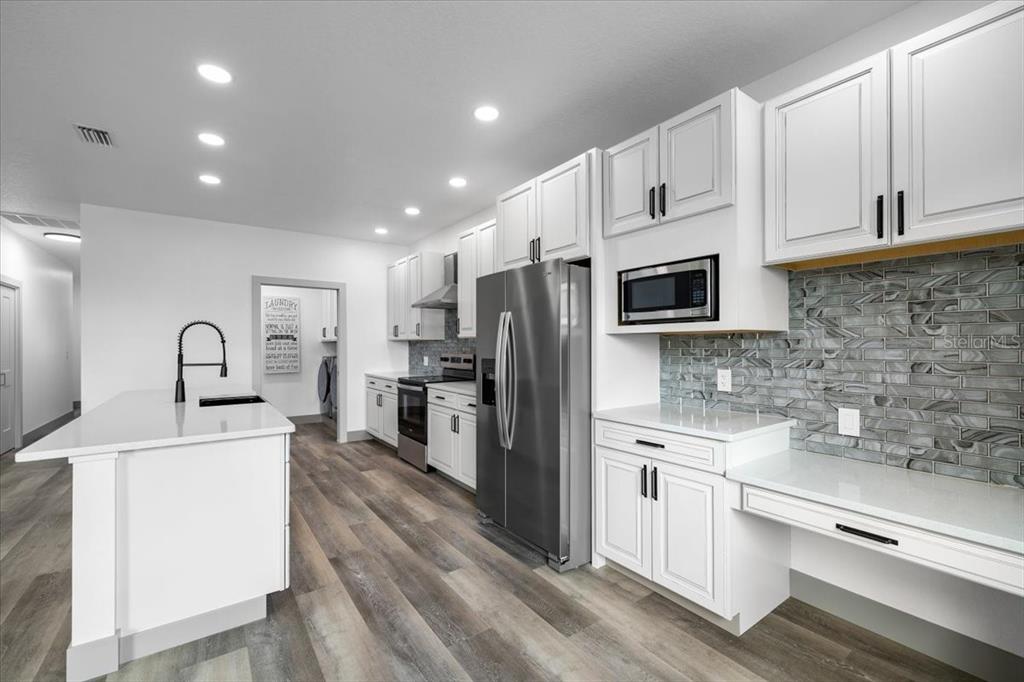 5056 Oak Leaf Lane Hernando Beach, FL 34607 - Photo 7 of 34 a kitchen with white cabinets and stainless steel appliances