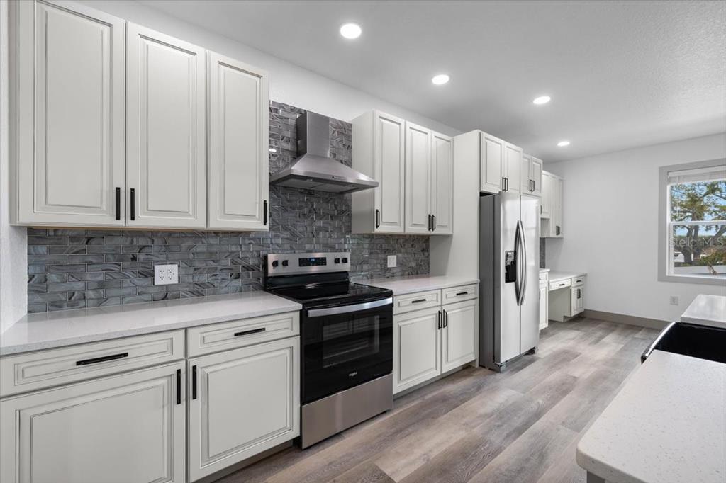 5056 Oak Leaf Lane Hernando Beach, FL 34607 - Photo 8 of 34 a kitchen with white cabinets and stainless steel appliances
