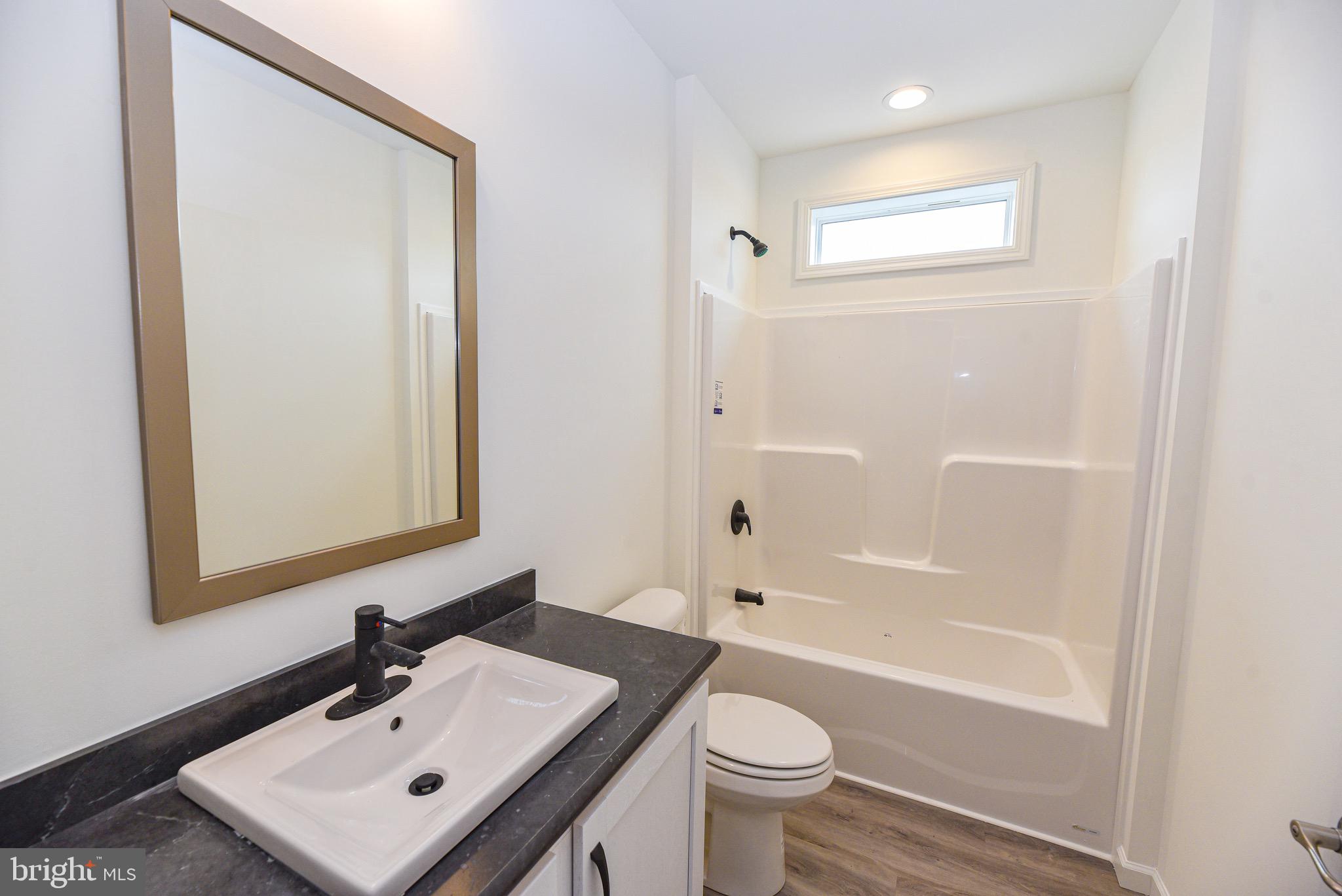 26363 West Pintail Road, Unit 78 Millsboro, DE 19966 - Photo 19 of 40 a bathroom with a sink toilet a mirror and shower