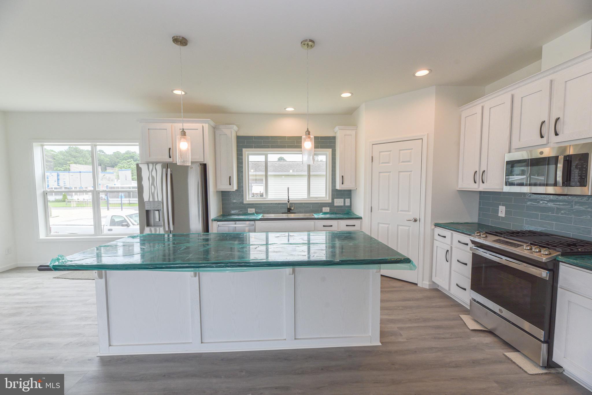 26363 West Pintail Road, Unit 78 Millsboro, DE 19966 - Photo 26 of 40 a kitchen with kitchen island granite countertop a stove and a sink