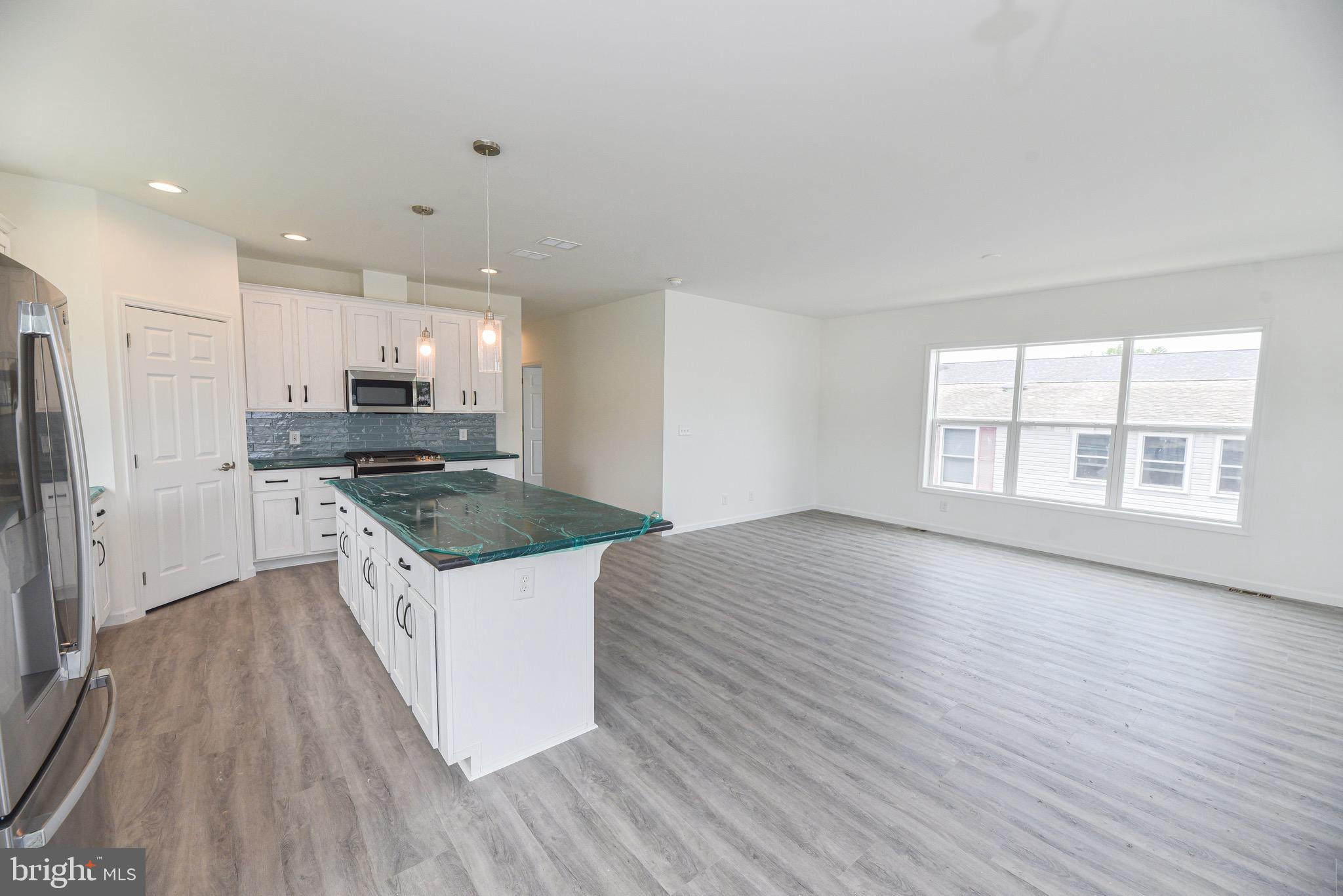 26363 West Pintail Road, Unit 78 Millsboro, DE 19966 - Photo 32 of 40 a large kitchen with stainless steel appliances granite countertop a stove a sink and a refrigerator