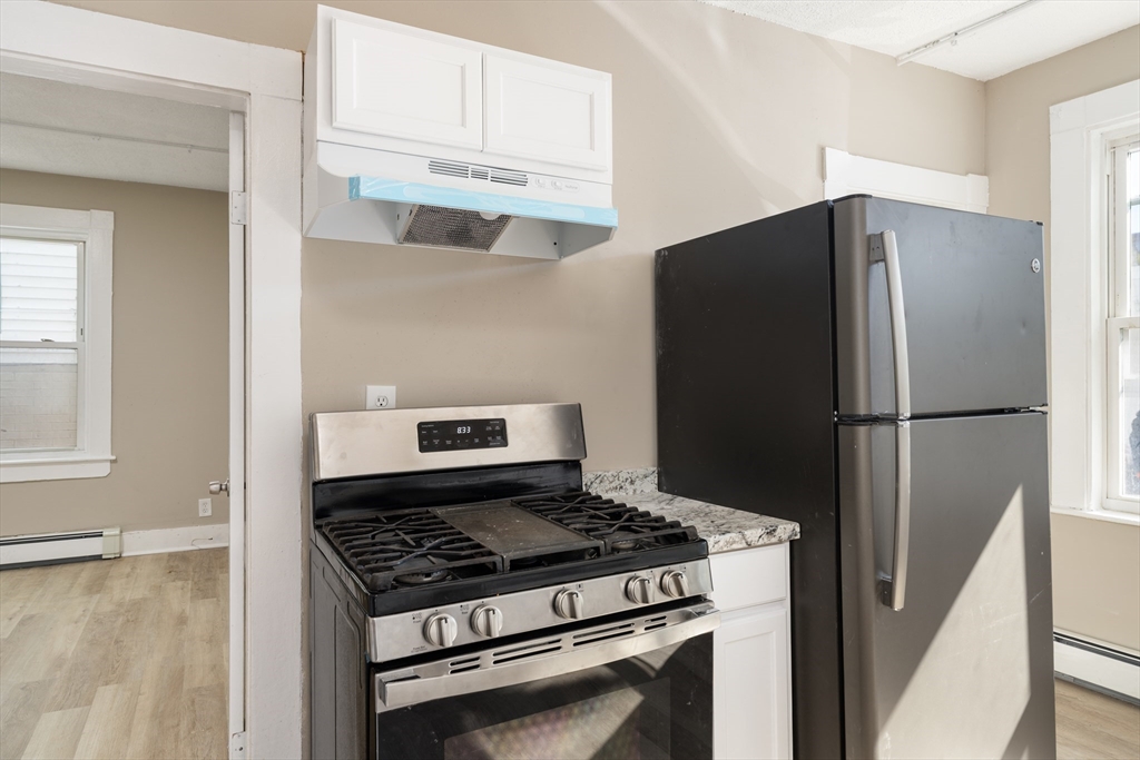 50 Common Street, Unit 5 Lawrence, MA 01840 - Photo 6 of 28 a kitchen with stainless steel appliances a refrigerator a stove and white cabinets