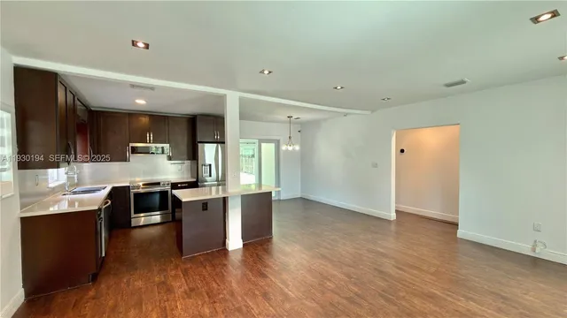 a kitchen with stainless steel appliances kitchen island granite countertop a stove a sink and a refrigerator