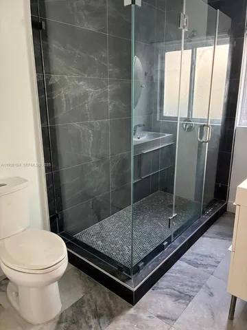 a bathroom with a granite countertop bathtub shower and toilet