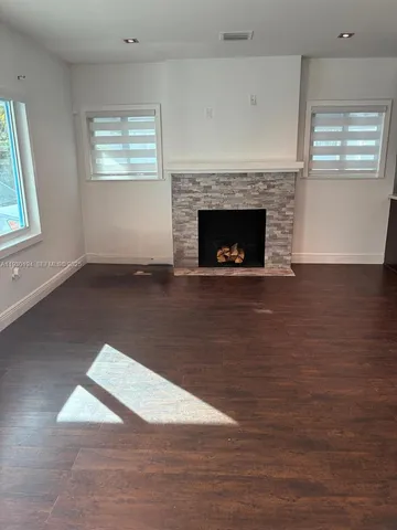 an empty room with wooden floor a fireplace and windows
