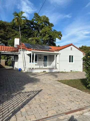 a view of a white house with a yard and potted plants