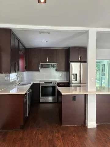 a kitchen with stainless steel appliances kitchen island granite countertop a stove a sink and a microwave