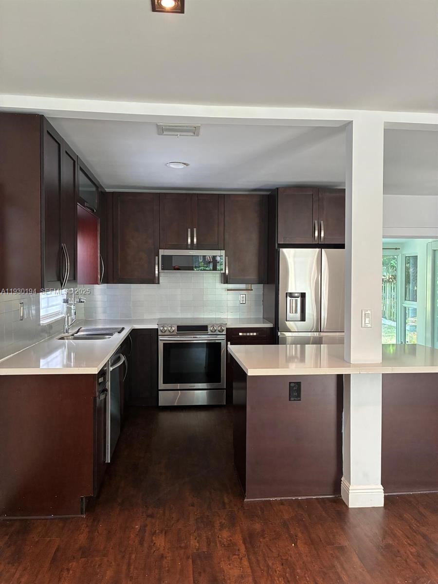 1757 Southwest 24th Terrace Miami, FL 33145 - Photo 9 of 40 a kitchen with stainless steel appliances kitchen island granite countertop a stove a sink and a microwave