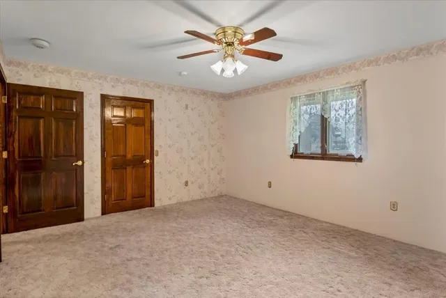 a view of an empty room with window and a ceiling fan