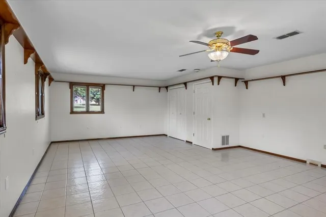 an empty room with windows and fan