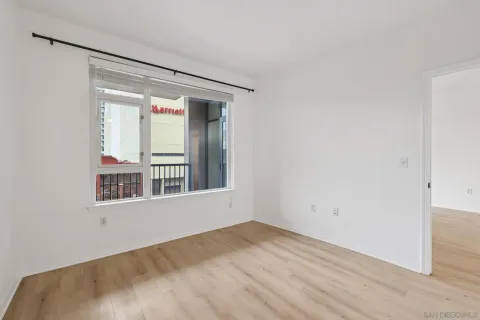 a view of an empty room with wooden floor and a window
