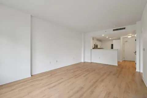 a view of a big room with wooden floor and a kitchen