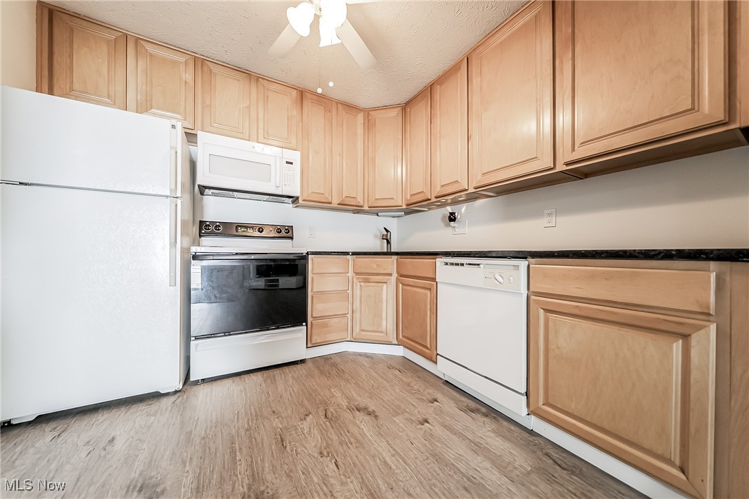 882 Overlook Ridge Drive Cleveland, OH 44109 - Photo 6 of 26 Kitchen featuring white appliances, light brown cabinetry, dark countertops, light wood-type flooring, and ceiling fan