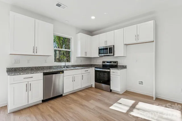 a kitchen with stainless steel appliances granite countertop a stove a sink and a microwave
