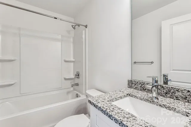 a bathroom with a granite countertop tub sink and mirror